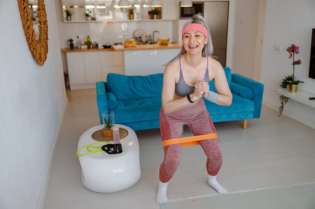 cheerful-woman-using-resistance-band-during-home